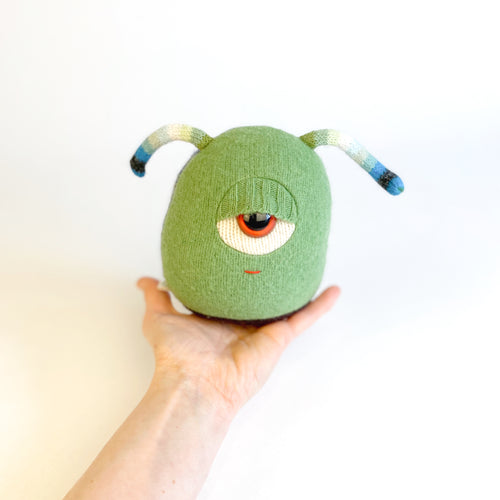 green cyclops monster toy with striped antennae