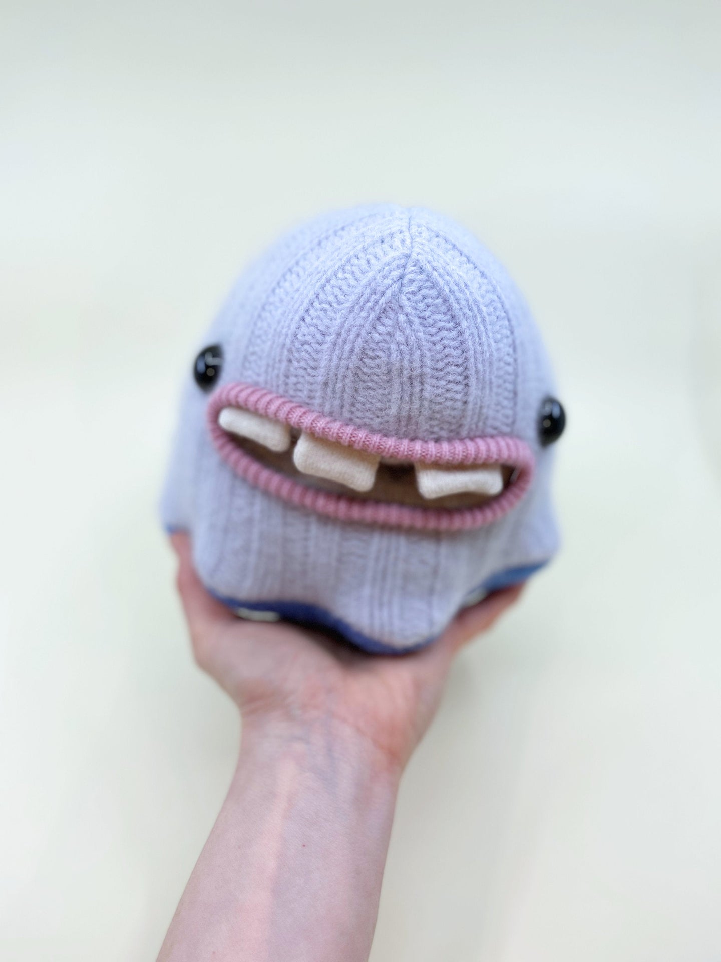 cute sweater monster with three teeth and pocket mouth