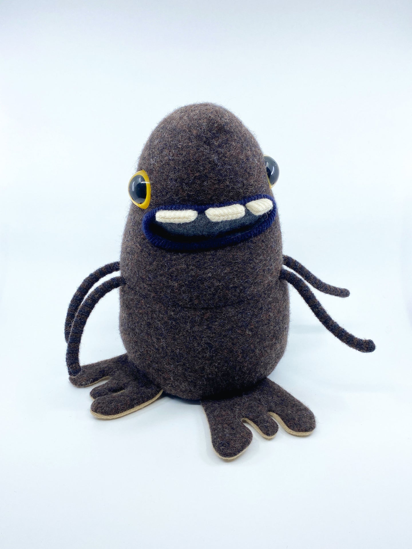 dark brown sweater monster with three teeth and four arms
