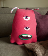 Load image into Gallery viewer, pink two eyed monster sitting on couch
